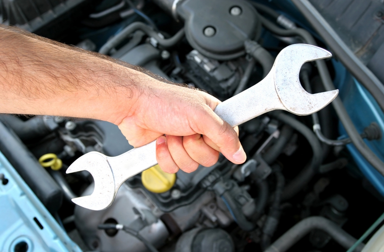 Mechanic with a wrench over an engine.